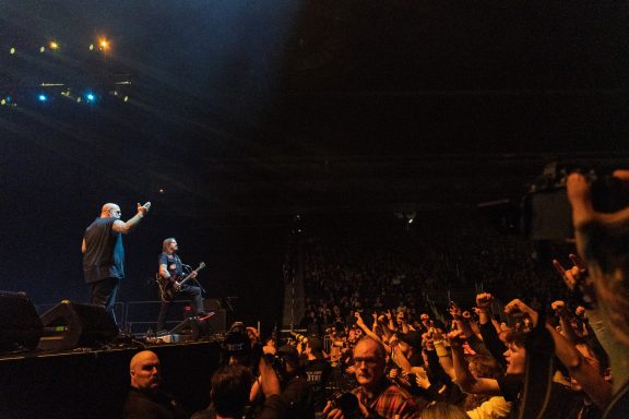 Exodus - Centre Videotron A performer sings on stage while fans cheer and raise their hands in excitement.