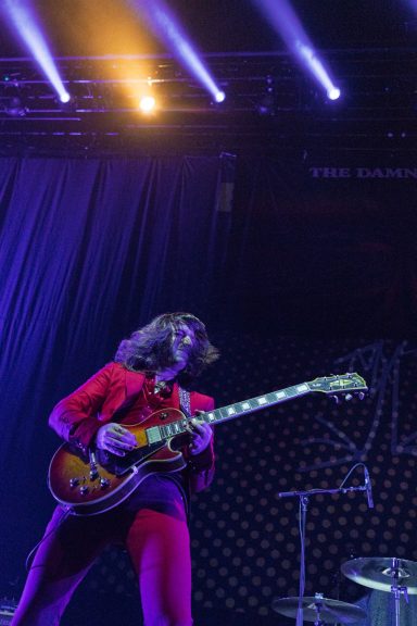 The Damn Truth - Centre Videotron Musician in a red suit playing guitar on stage with dramatic lighting.