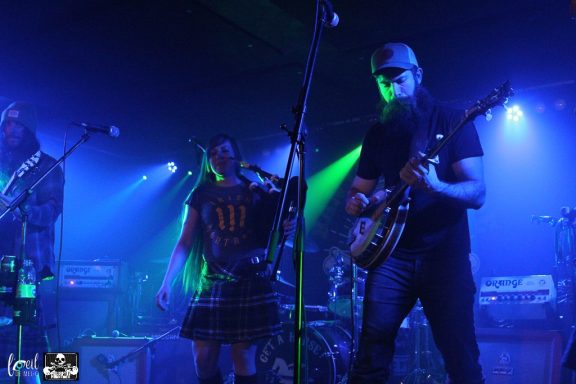 Band performing on stage with colorful lights and instruments.