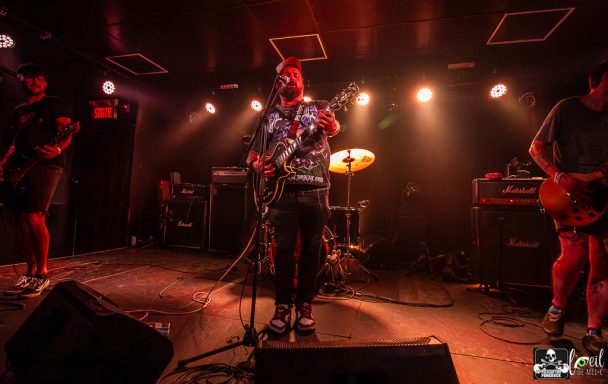 Band performing on stage with lights and instruments, energetic atmosphere.