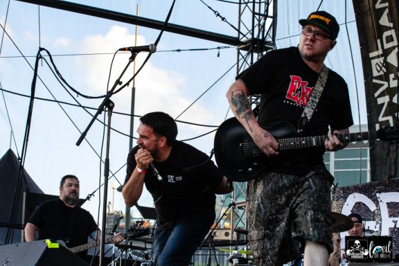 Band performing on stage with a vocalist and guitarist, energetic atmosphere.