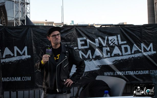 Man in a leather jacket standing in front of a branded banner.