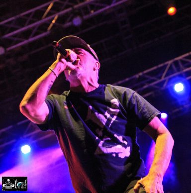 Singer performing on stage with a microphone and vibrant stage lights behind.