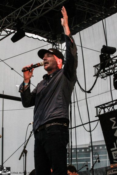 A singer performing on stage, gesturing with a microphone in hand.