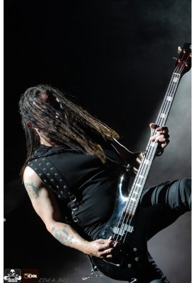 Musician playing electric guitar with long hair in a dramatic lighting setting.