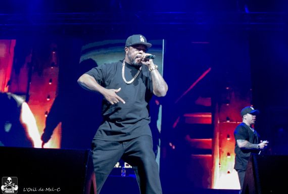 A rapper performing on stage with energetic gestures and a microphone.