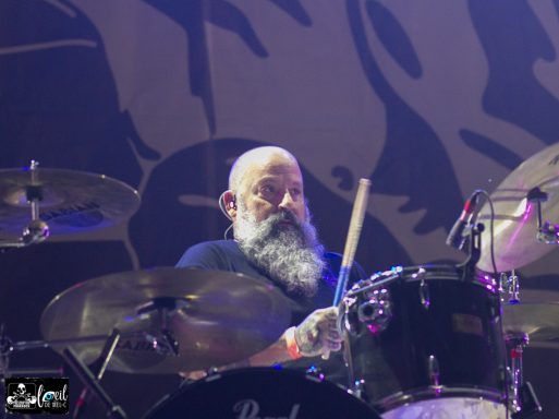 Musician playing drums, featuring a man with a beard and focused expression.