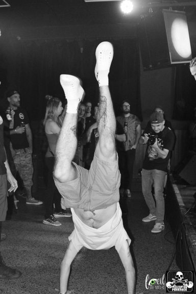 Person performing a handstand in a crowd at an event, with low light and a dynamic atmosphere.
