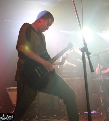 Mvll Crimes - La Source de la Martinière Musician playing guitar on stage with dramatic lighting effects.