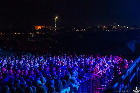 Crowd at a nighttime concert, illuminated by vibrant stage lights.