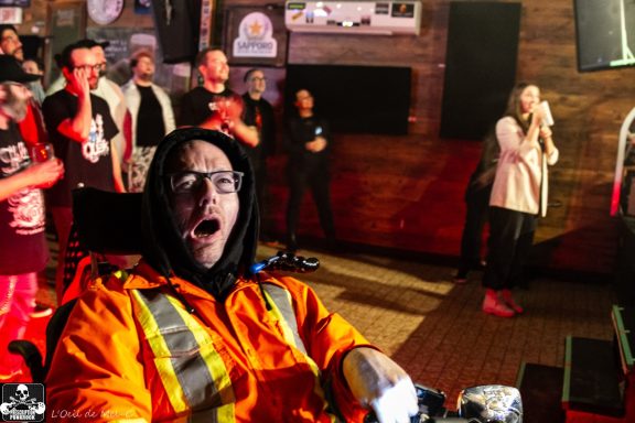 A surprised individual in safety gear with a crowd in the background.