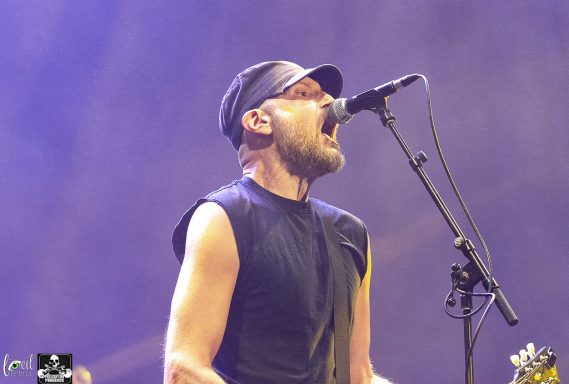 Musician singing passionately into a microphone on stage.