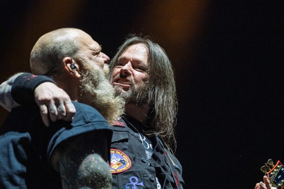 Two musicians embrace on stage, sharing an intimate moment during a performance.