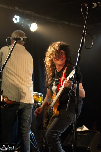 Dead Bob - La Source de la Martinière A musician playing bass guitar on stage, with dramatic lighting and an energetic expression.