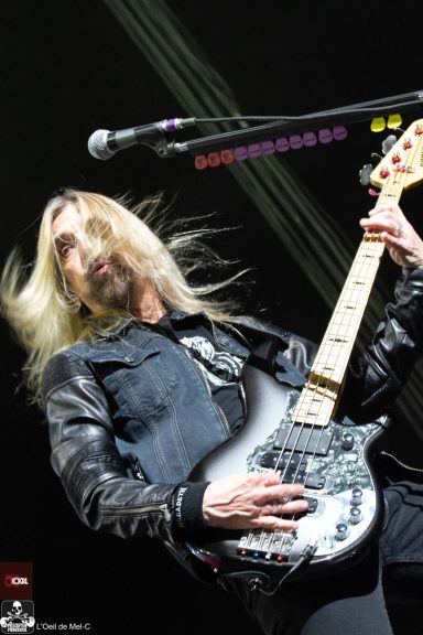 Musician with long hair playing an electric guitar on stage.