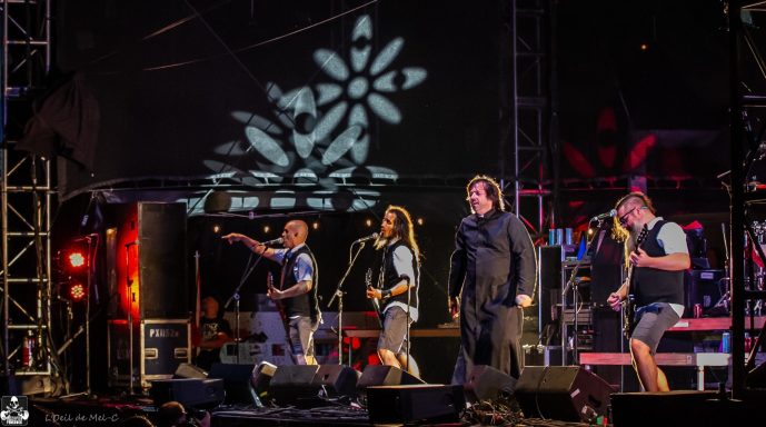 A band performing on stage with colorful lights and a flower pattern backdrop.