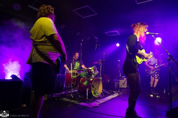 Musicians performing on stage with colorful lighting and smoke effects.
