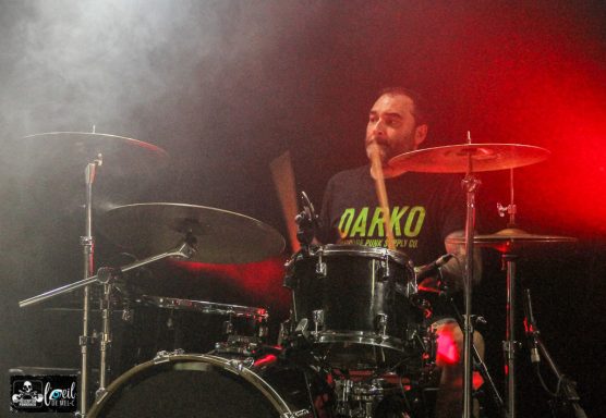 Straightline - L'Anti-Bar & Spectacles Drummer in a vibrant performance, wearing a "BARKO" shirt, with dramatic lighting.