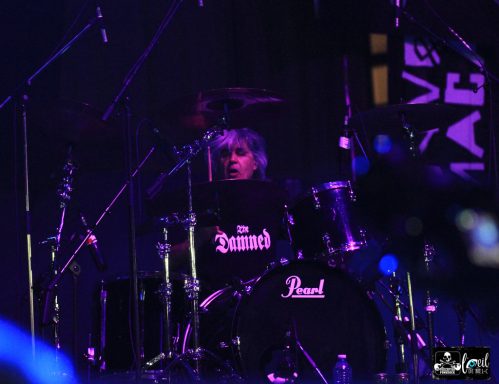 Drummer performing on stage with colorful lighting during a live concert.