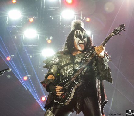 Rock musician in costume performing on stage with a guitar and dramatic lighting.