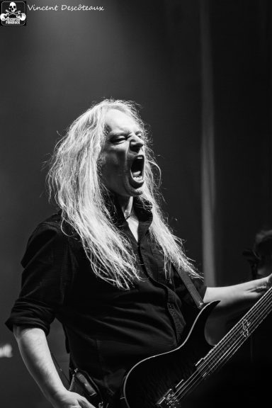 A musician passionately performing on stage, singing into a microphone.