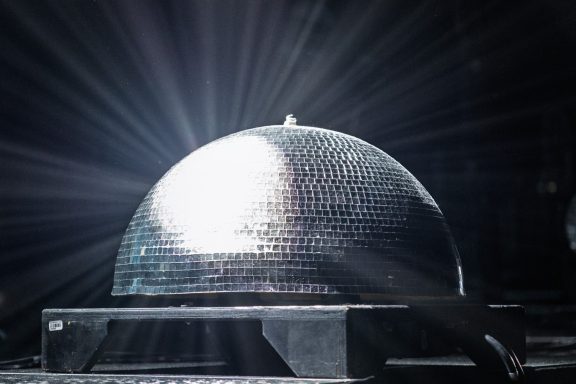 +LIVE+ - Centre Videotron Shiny disco ball reflecting light beams in a dark setting.