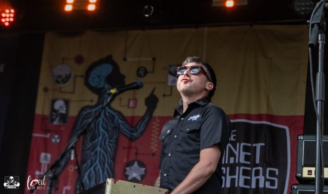 Musician performing on stage with a vibrant backdrop featuring graphic art.