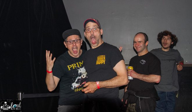 Straightline - L'Anti-Bar & Spectacles Two excited men pose with expressive faces, while two others stand in the background.