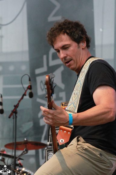 Musician playing guitar on stage during a live performance.