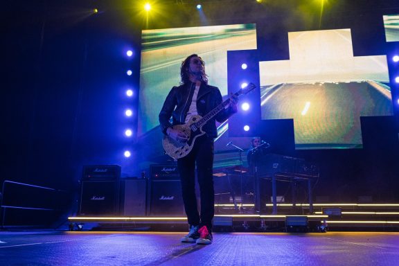 +LIVE+ - Centre Videotron Musician playing guitar on stage with colorful lights and screens in the background.