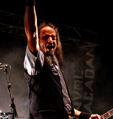 A musician passionately performing on stage with a raised arm and intense expression.