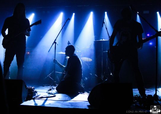 Silhouetted band performing on stage with dramatic blue lighting.