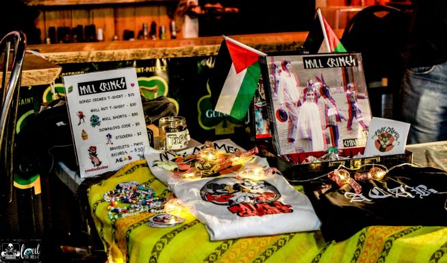 Mvll Crimes - La Source de la Martinière A display of Palestinian merchandise, including t-shirts, flags, and informational signs.