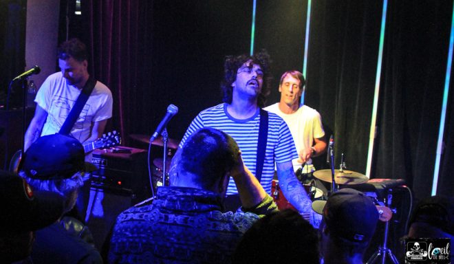 Band performing live on stage with an audience focused on the musicians.
