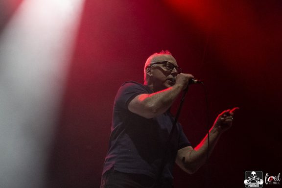 Singer performing on stage with dramatic lighting.
