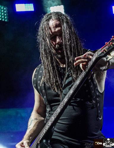 A musician with long, dreadlocked hair plays an electric guitar on stage.