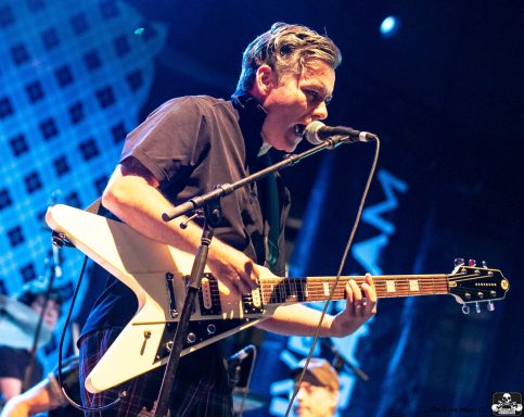 Musician passionately performing on stage with an electric guitar.