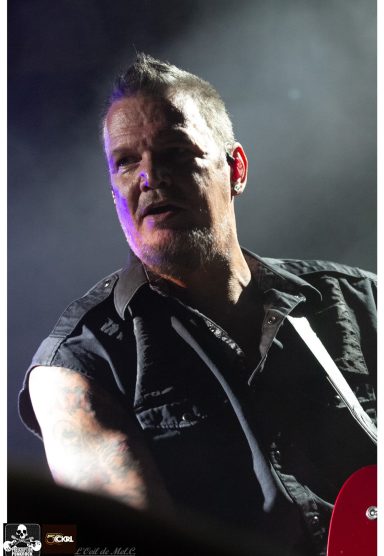 A close-up of a man performing on stage, wearing a black shirt and looking intently.