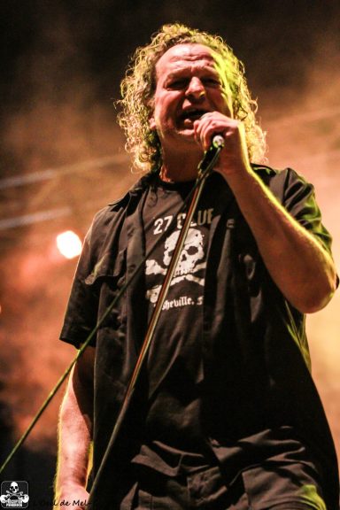 Singer passionately performing on stage with a microphone, wearing a black shirt.