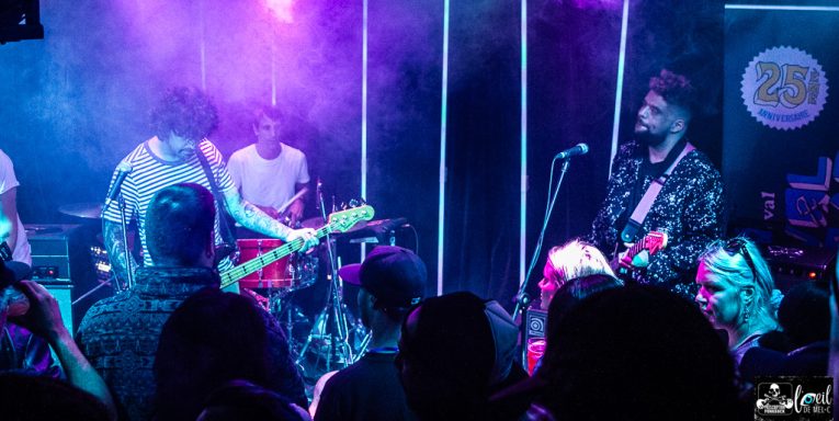 A live band performing on stage with colorful lights and an engaged audience.