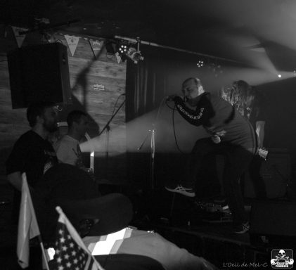 Black and white scene of a live performance with musicians and audience members.