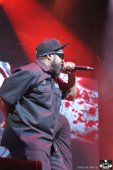 Male performer singing on stage with a dramatic red lighting backdrop.