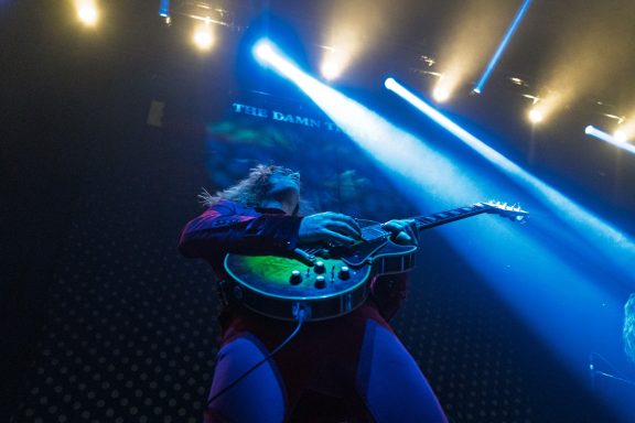 The Damn Truth - Centre Videotron Musician playing guitar passionately on stage with bright lights in the background.