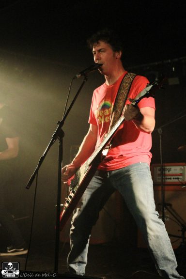 A musician passionately performing on stage with a guitar and microphone.