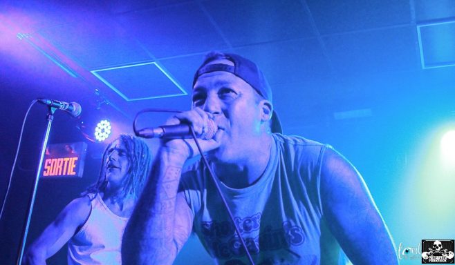 A singer performs passionately on stage with colorful lighting.