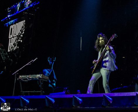 A musician plays bass on stage, with a keyboard visible in the background.