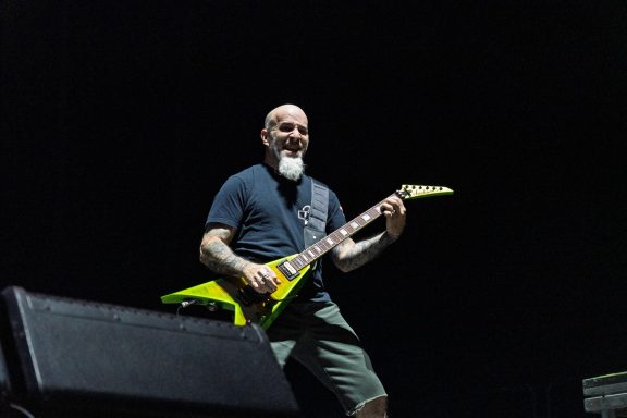 Man playing a yellow guitar on stage with a focused expression.