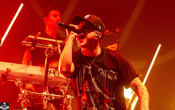 A singer performing passionately with a band in a vibrant, colorful stage setting.