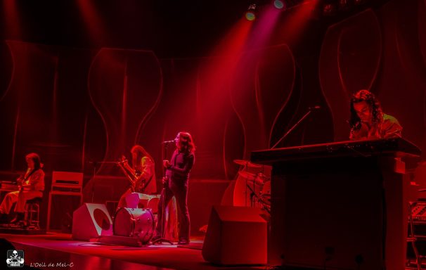 Band performing on stage with red lighting and various instruments.