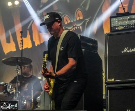Millencolin - Red Bridge Fest 2026 A musician plays guitar on stage with a band, featuring amplifiers and colorful lighting.